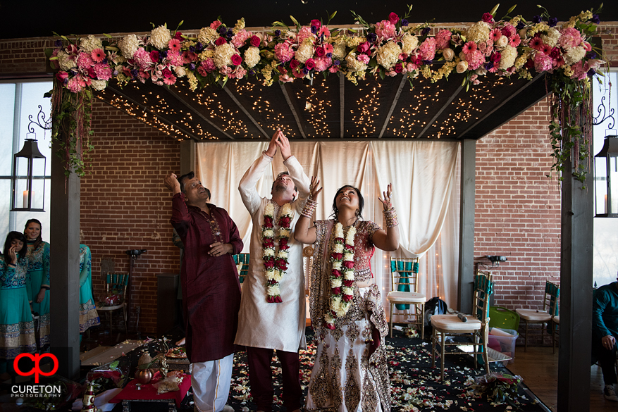 Bride and groom throw rice into the air during their Indian wedding in Greenville,SC..