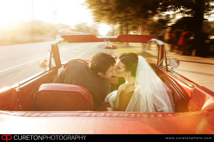 A couple leaving thier wedding in a vintage Mustang convertable.