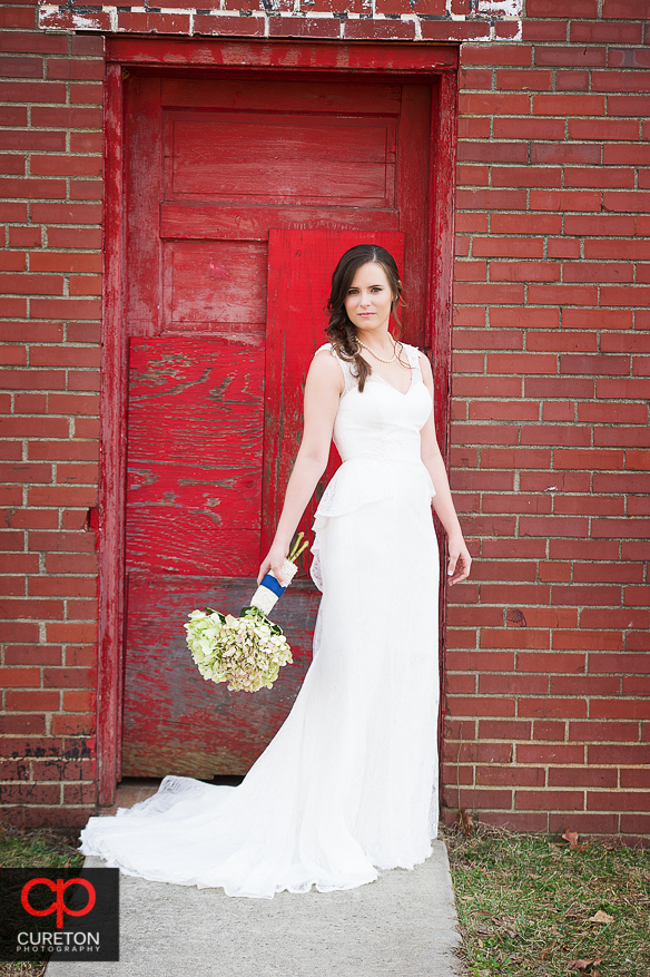 Bride posing with flowers in front of red door.