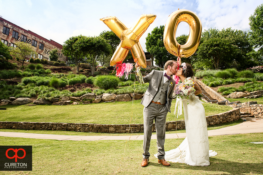 Couple on their wedding day holding X and O balloons in Falls Park in downtown Greenville,SC .