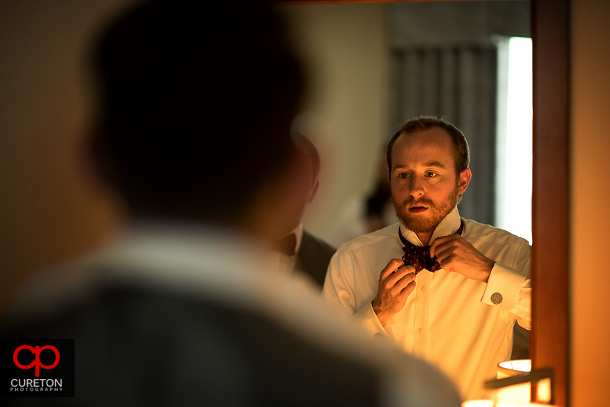 Groom fixing his bowtie.