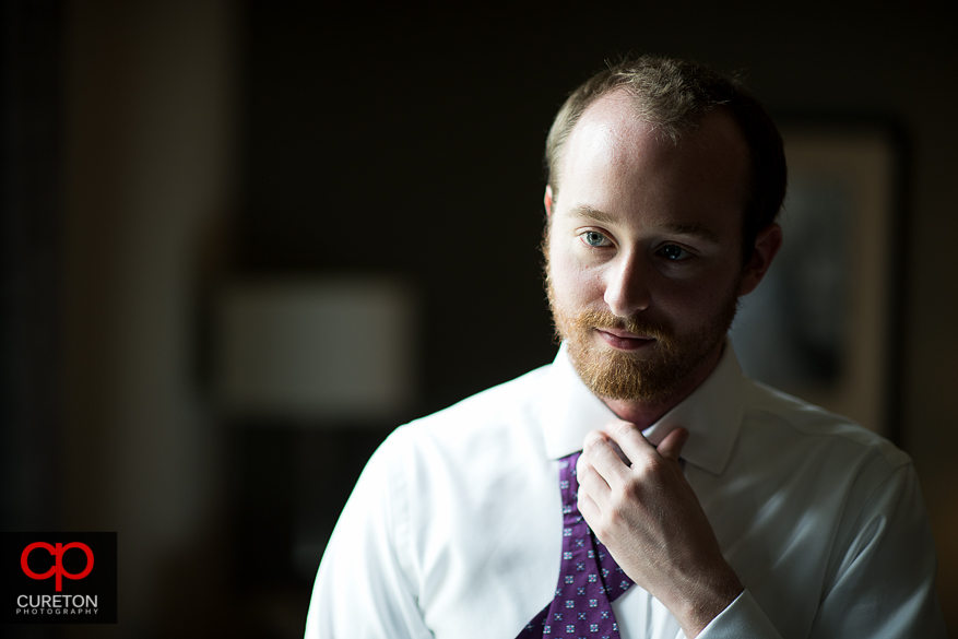 Groom fixing his bowtie before the wedding.