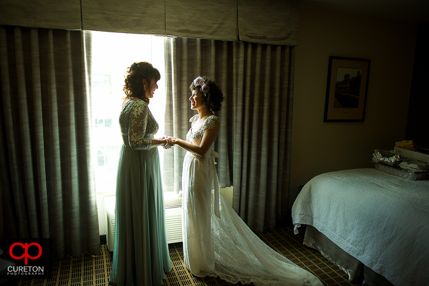 Bride and her mother share a moment in the window.