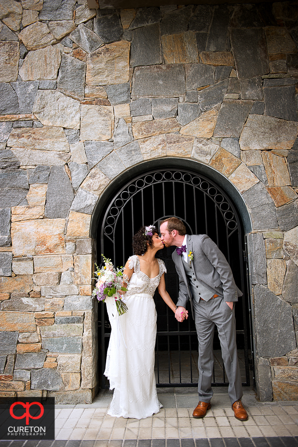 Bride and groom kissing in front of a gate.