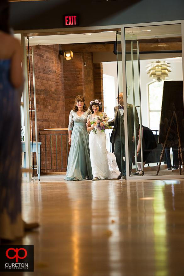 Bride escorted down the aisle by her parents.