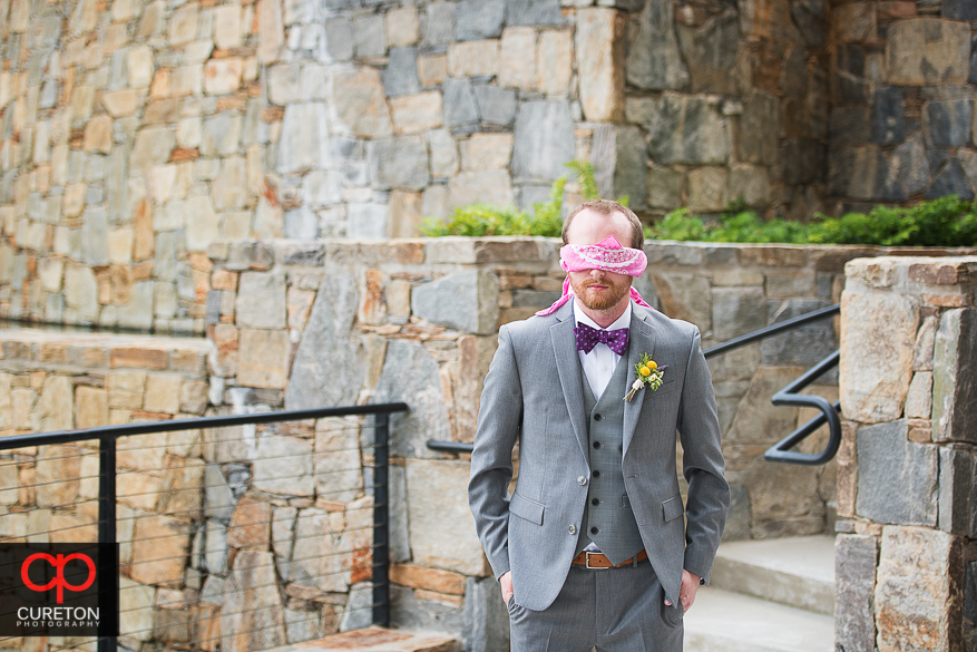 Groom awaitin the first look while blindfolded .