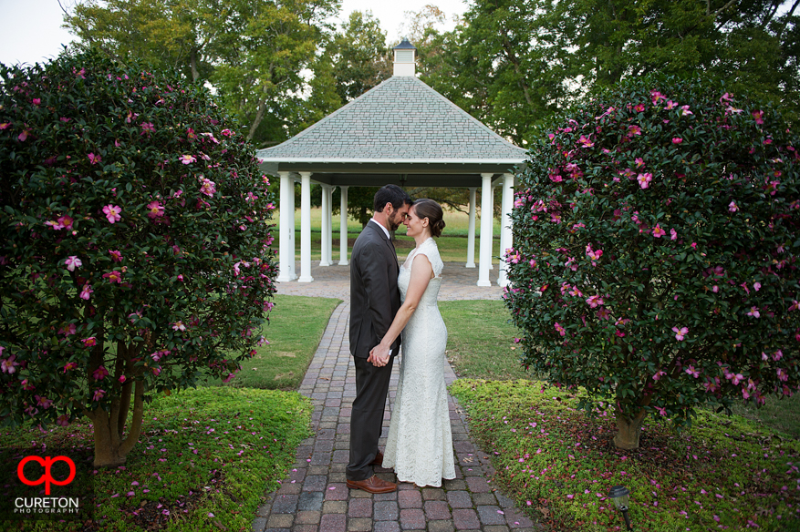 Bride and groom between bushes in courtyard.