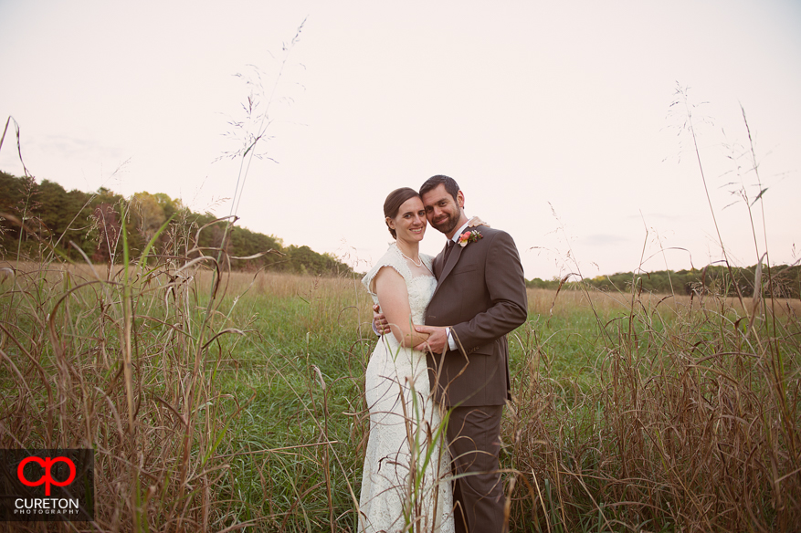 Bride and groom pose in a field.