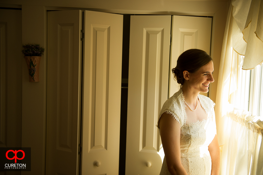 Bride standing in window light.
