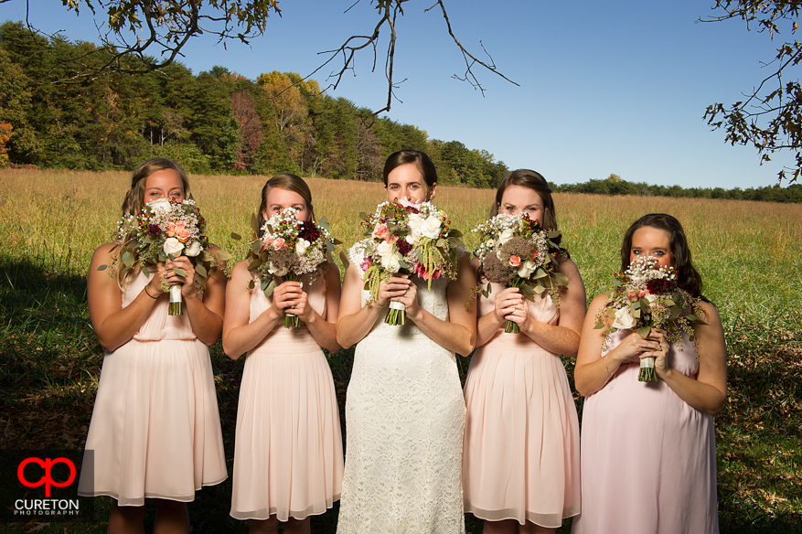 Bridesmaids with flowers covering their faces.