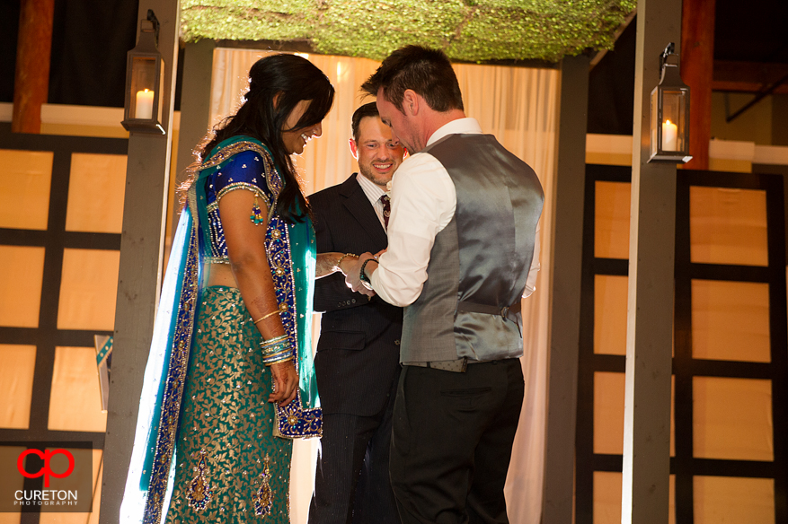 Groom putting a ring on the brides finger.