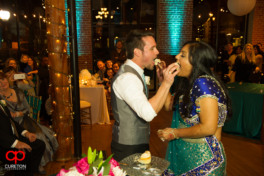 Bride and Groom feeding each other cake at their Indian wedding reception at The Loom.