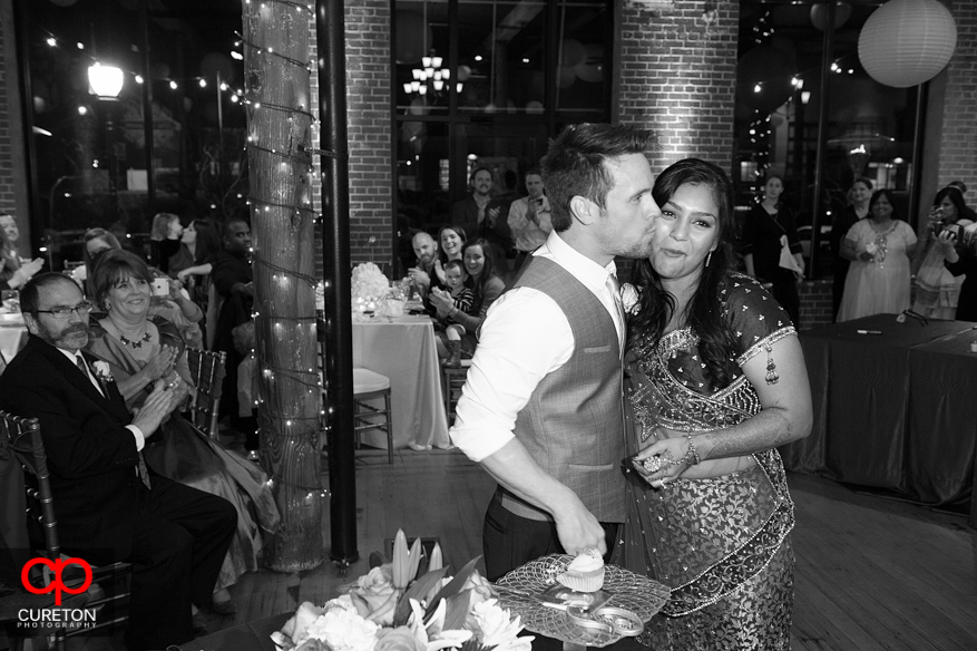 Groom kissing bride after cake cutting.