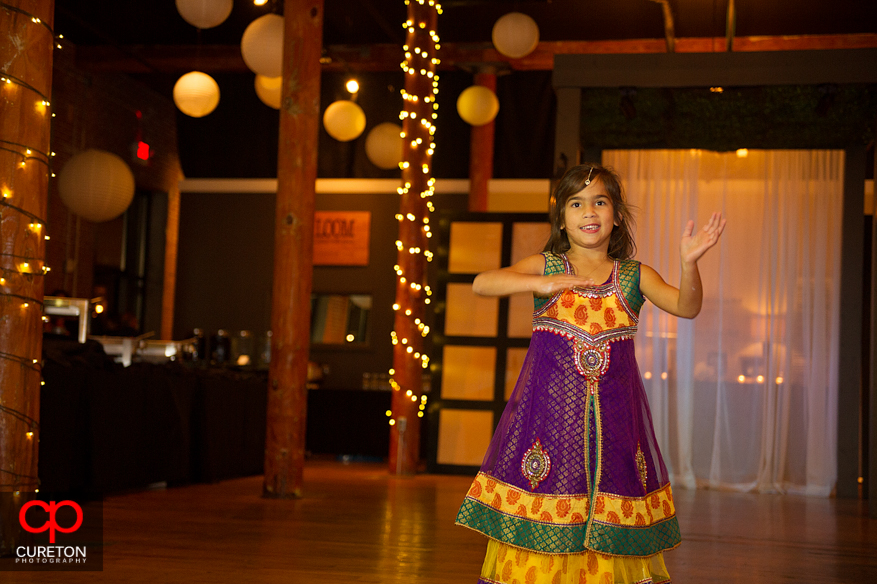 Flower girl dances at an Indian wedding reception.