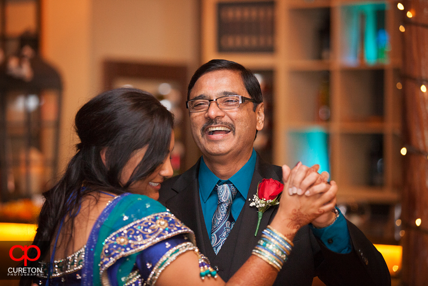 Father smiling at his daughter during a dance at their reception.