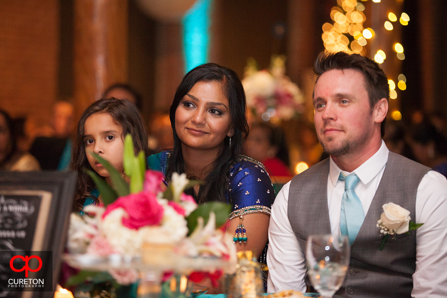 Bride and Groom look on as their family gives toasts.