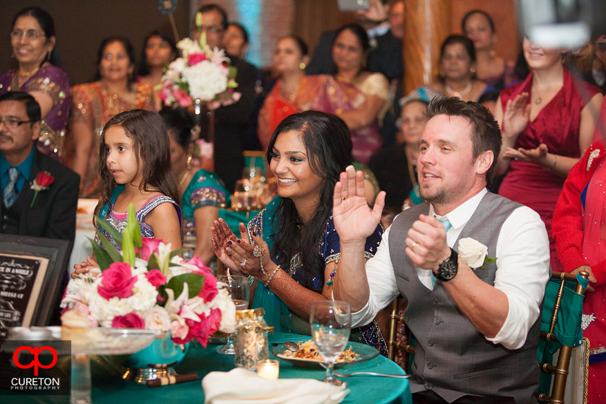 Bride and groom clap for the wedding performances.