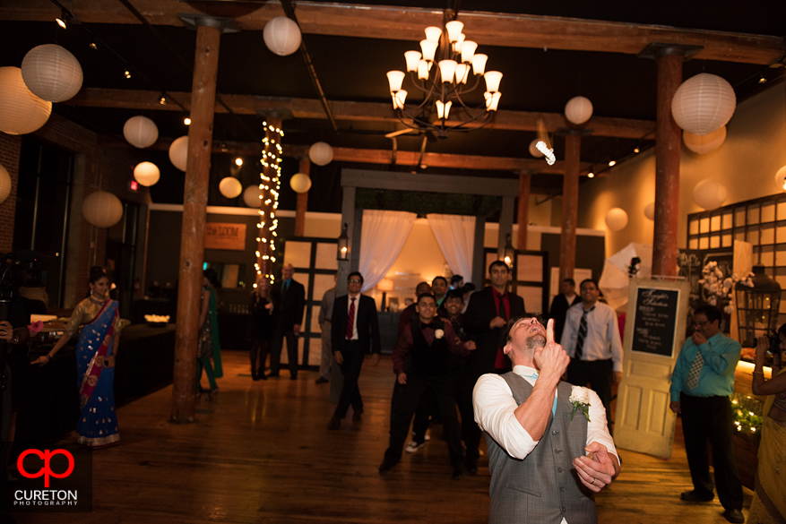 Groom tossing garter with it in mid-air.