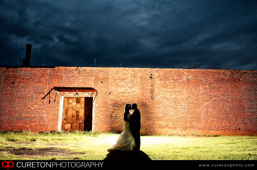 Creative backlit shot of bride and groom outside an old cotton mill in Simpsonville,SC.