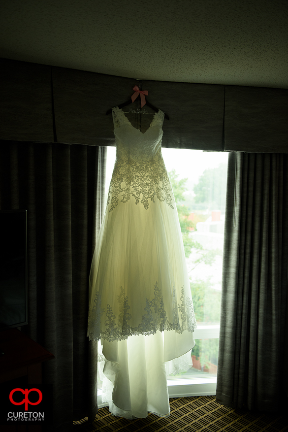 The brides dress hanging in a window.