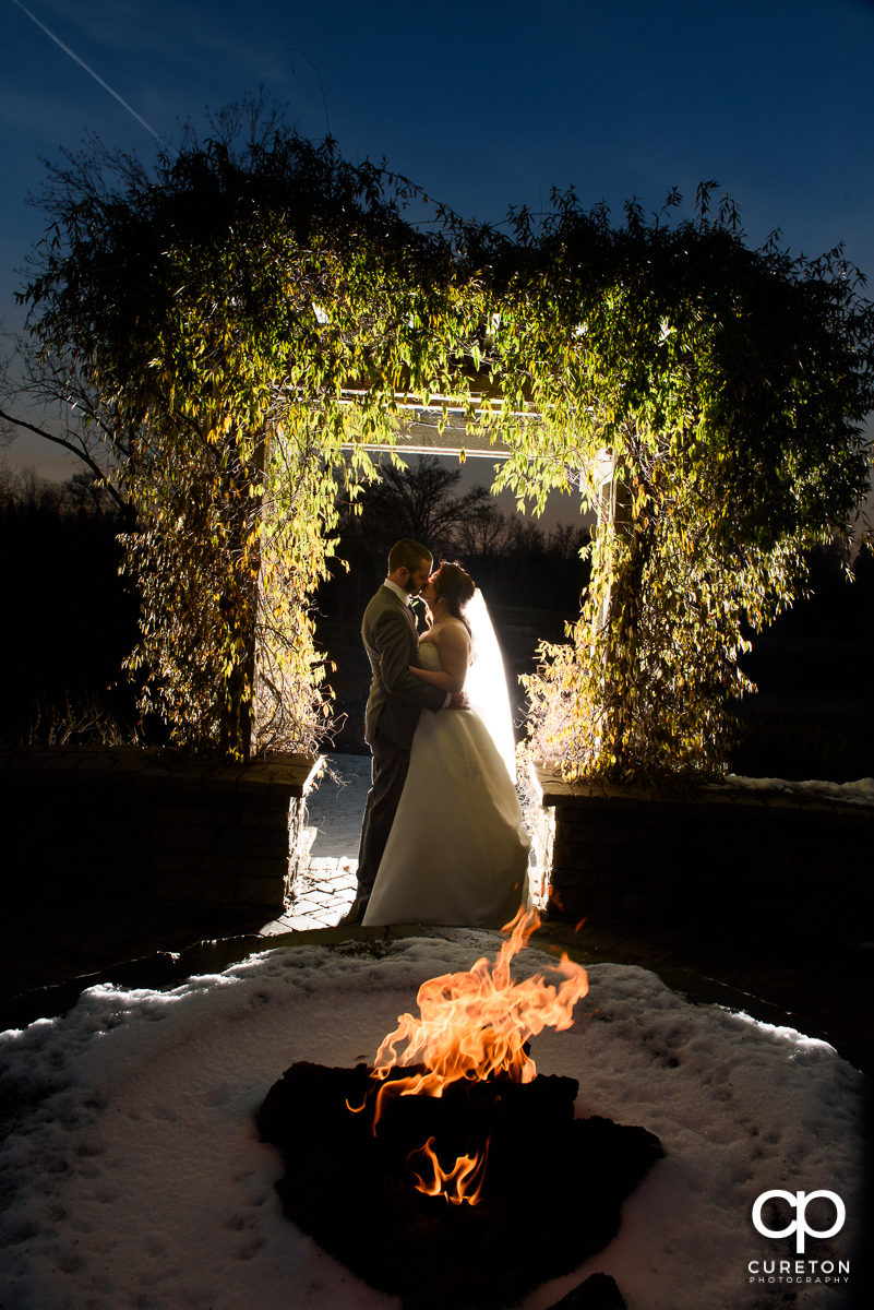 Brode and groom kissing by the fire pit after their wedding at The Arbors in Cleveland,NC.