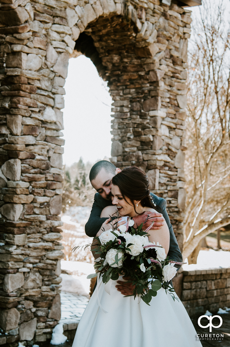Groom hugging his bride in the snow after their wedding at The Arbors in Cleveland,NC.