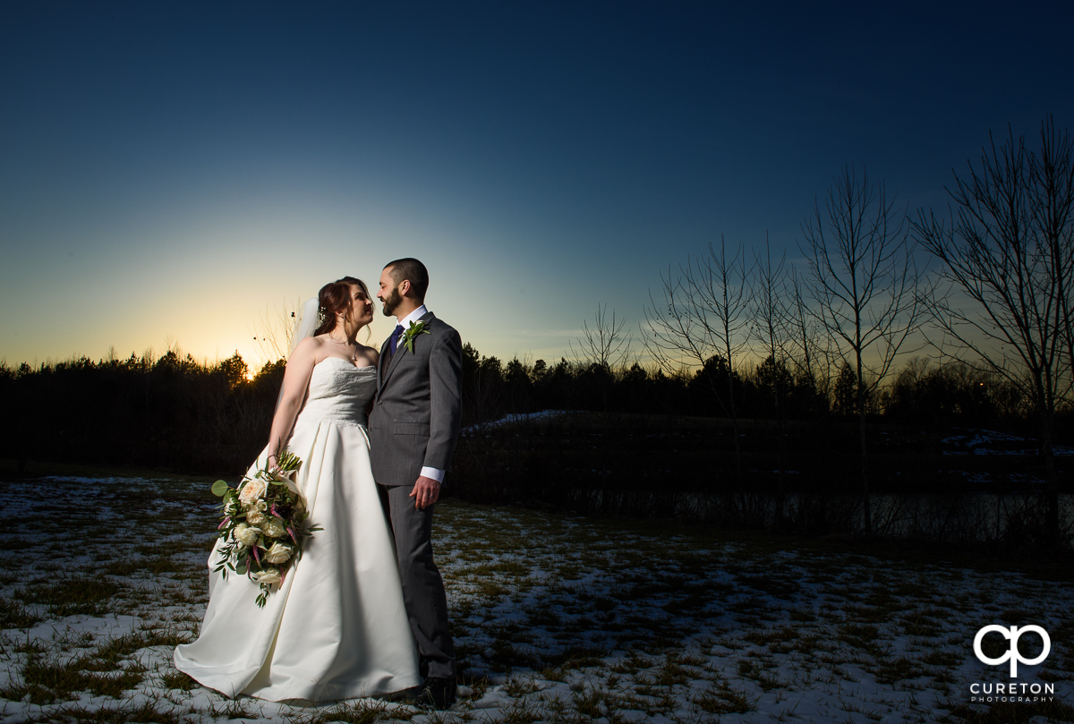Bride and groom in the snow at sunset after their wedding near Lake Norman.