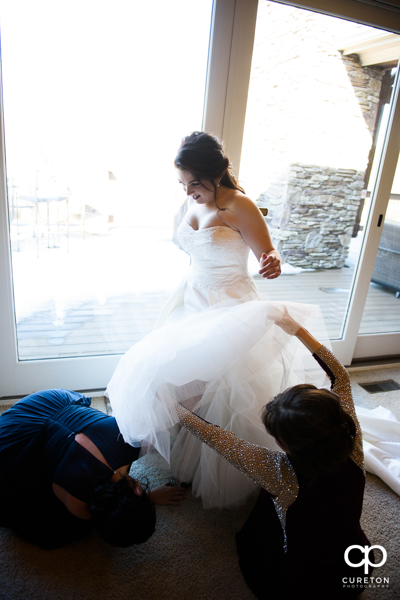 Bride getting helped into her dress.