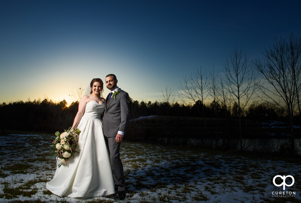 Bride and groom at sunset standing in the snow.