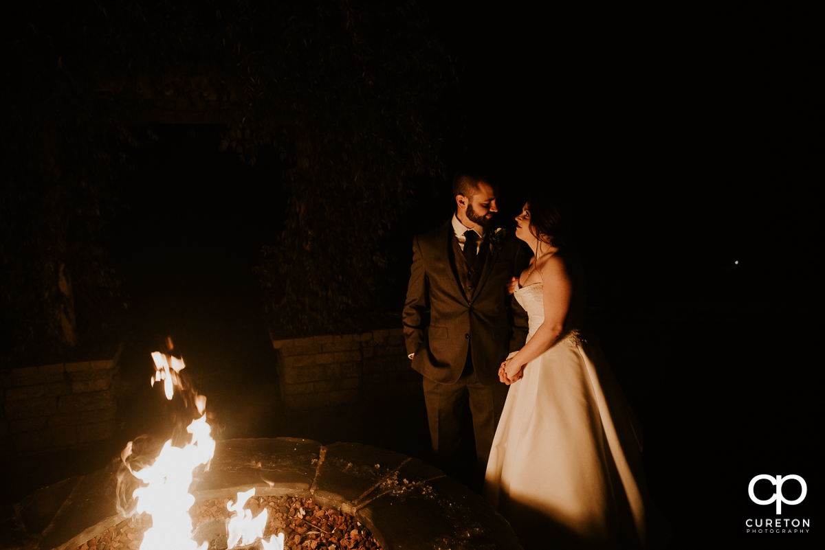 Bride and groom lit by the firepit at The Arbors in Cleveland,NC wedding reception.