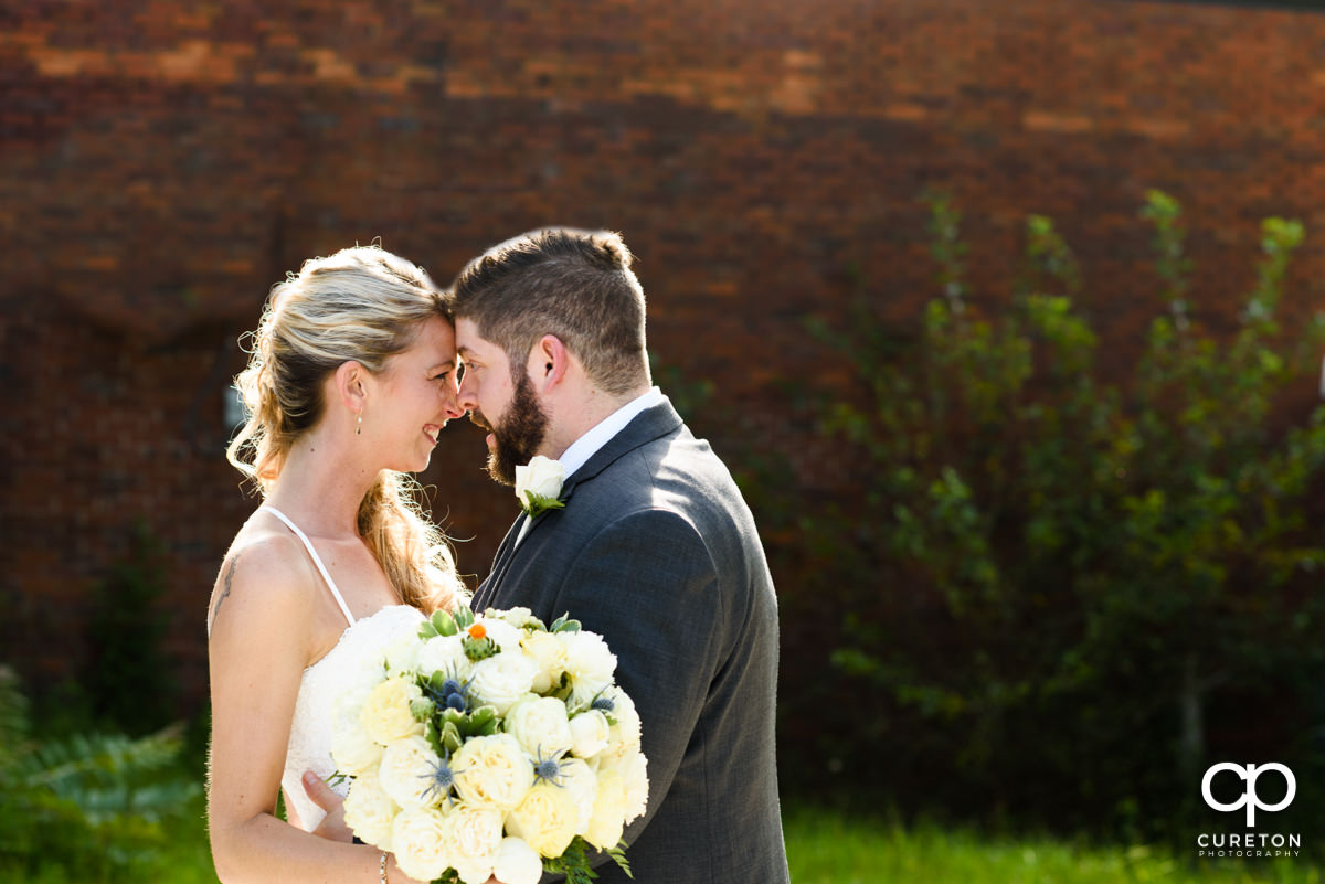 Bride and groom standing forehead to forehead outside Artisan Traders in Greenville.