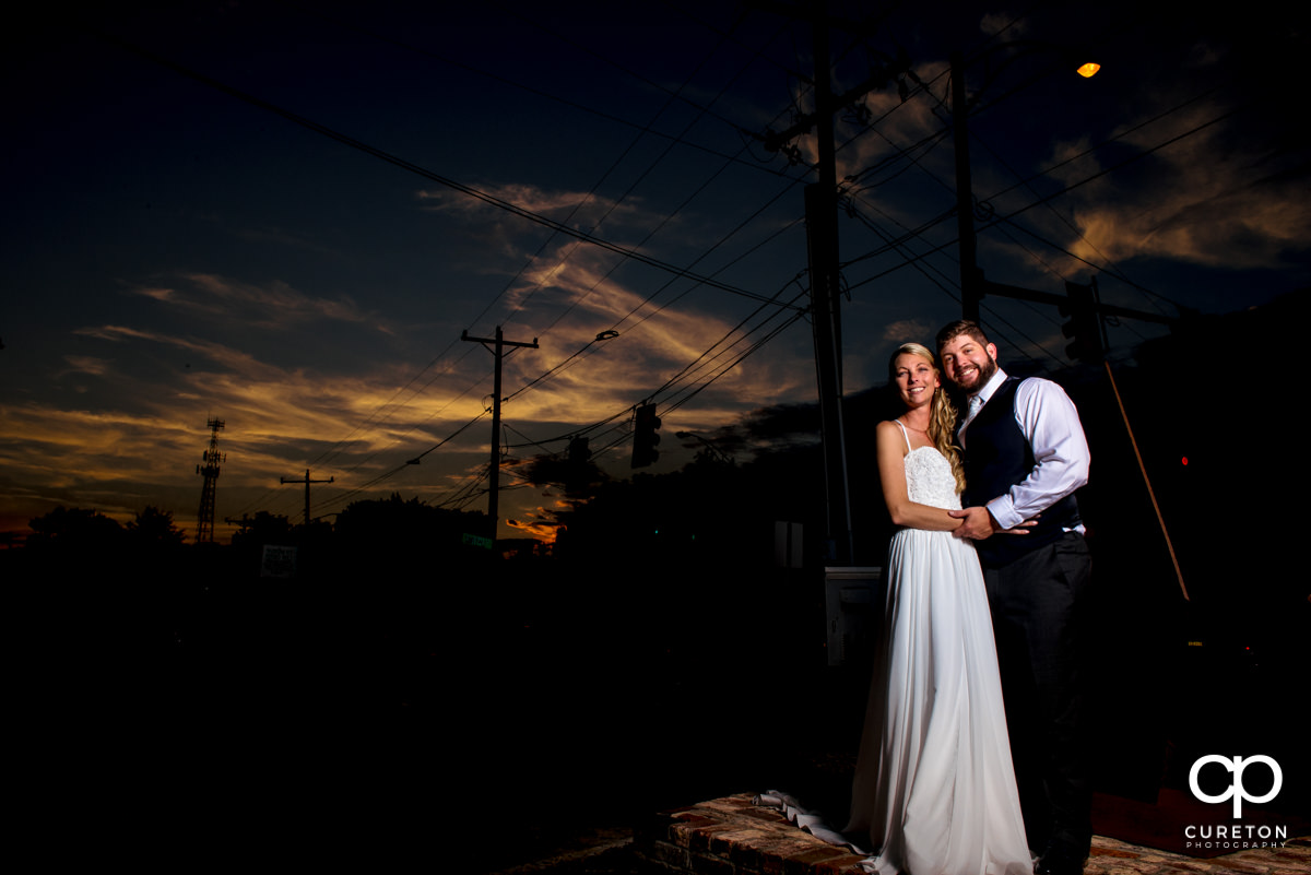 Bride and groom standing on a street corner at sunset in West Greenville.