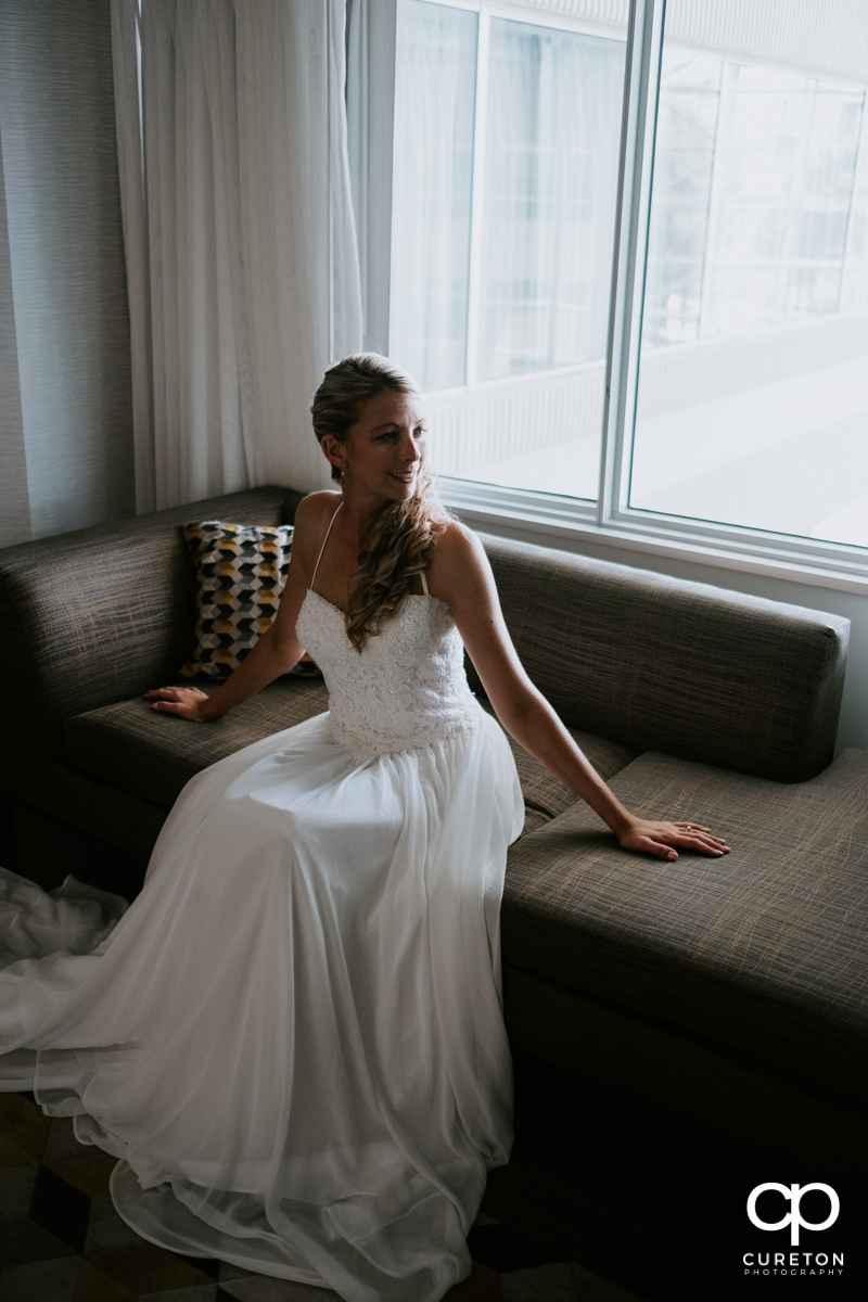 Bride sitting in window light at the Hyatt hotel before her wedding at Artisan Traders in Greenville,SC.