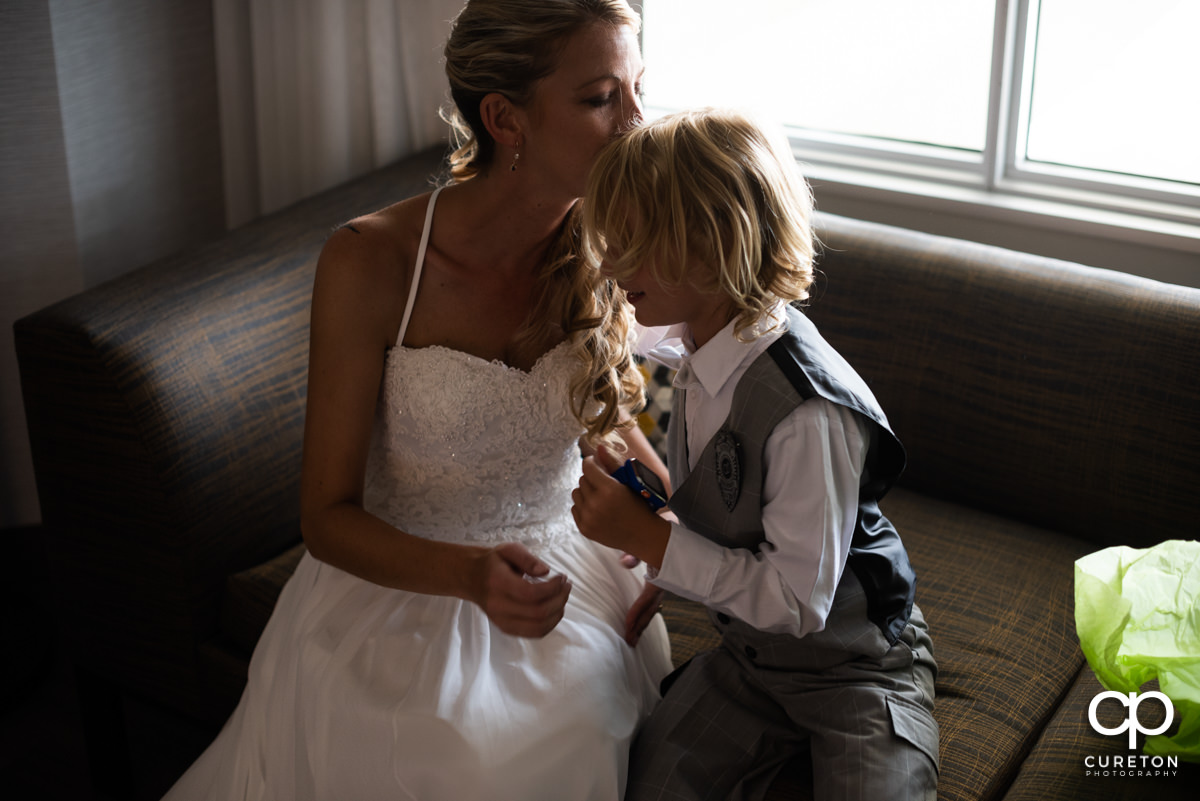 Bride kissing her young son on the forehead before her wedding ceremony.