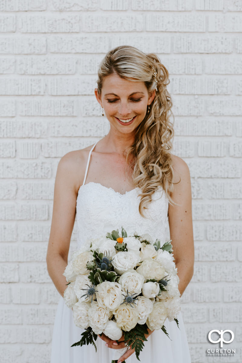 Bride looking at her bouquet outside of her Artisan Traders wedding.