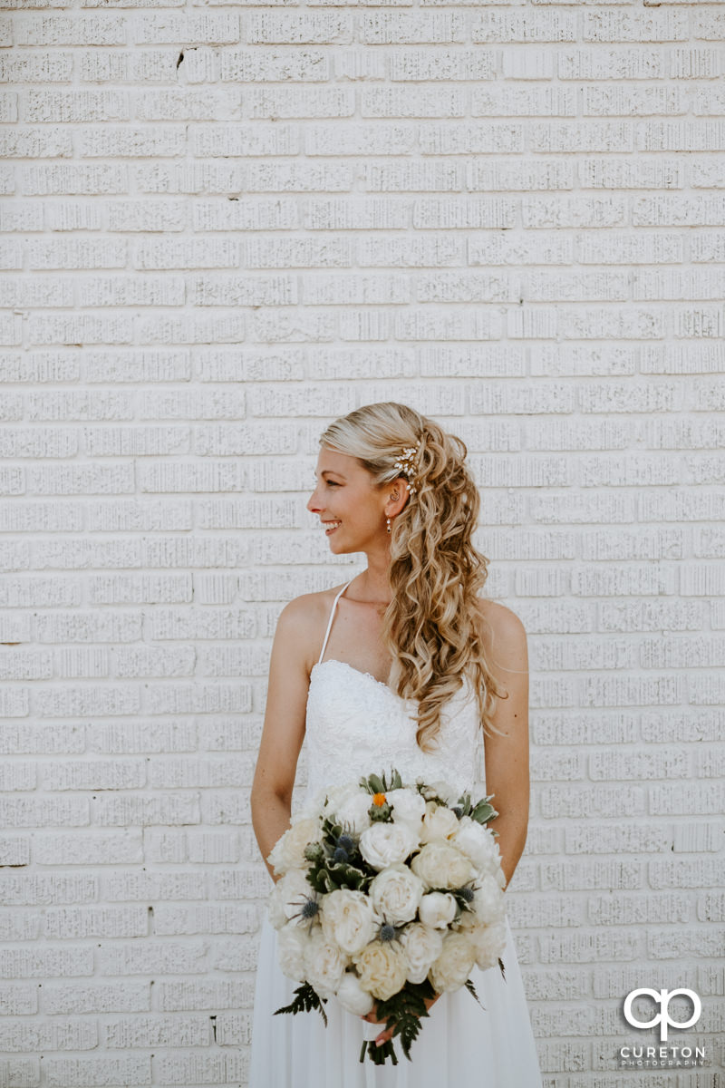 Bride standing against a white brick wall.