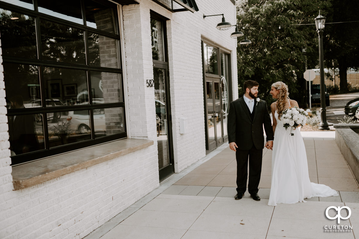 Bride and groom holding hands walking in West Greenville.