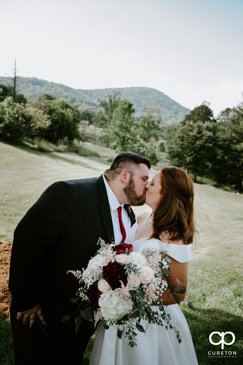 Bride and groom kissing underneath a tree after their Asheville NC outdoor wedding.