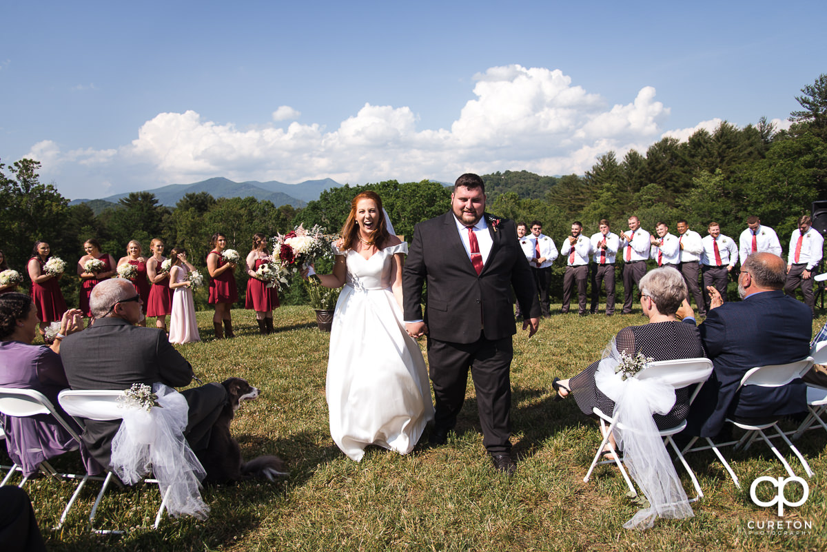 Bride and groom walking back down the aisle with the mountains behind them during the outdoor wedding ceremony in Asheville,NC.