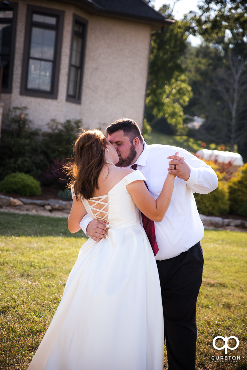 Groom kissing his bride as they share a dance at the wedding reception.