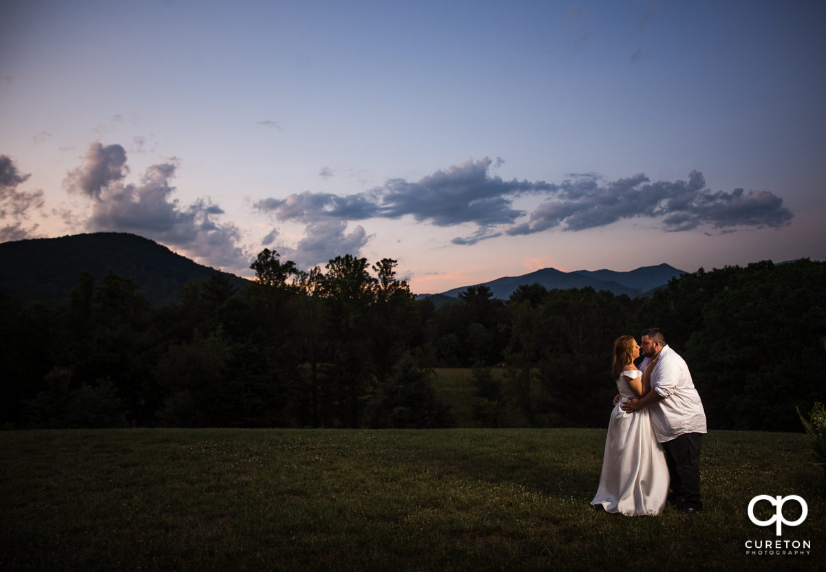 Bride and groom kissing during a mountain sunset.