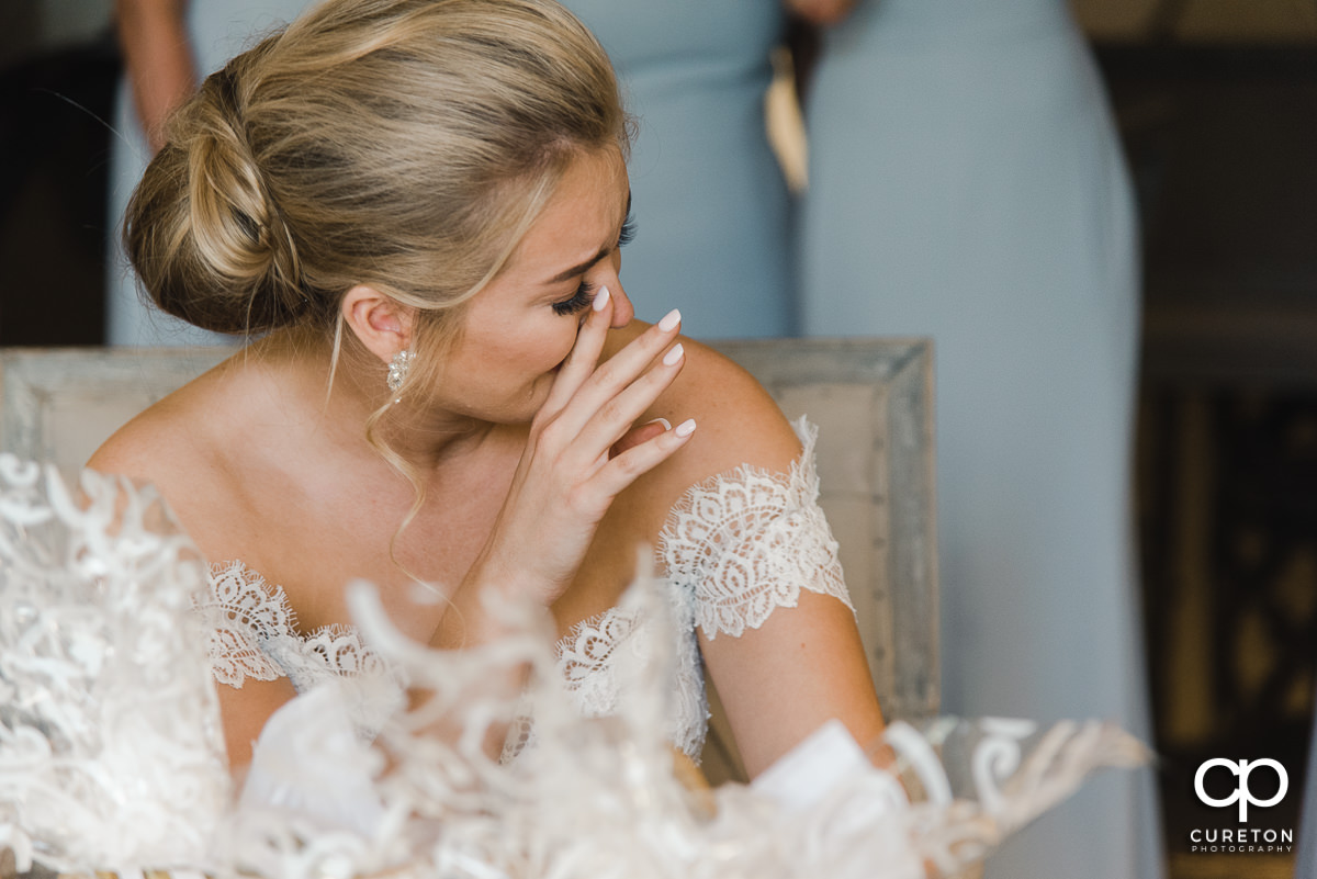 Bride tearing up while reading a card on her wedding day.