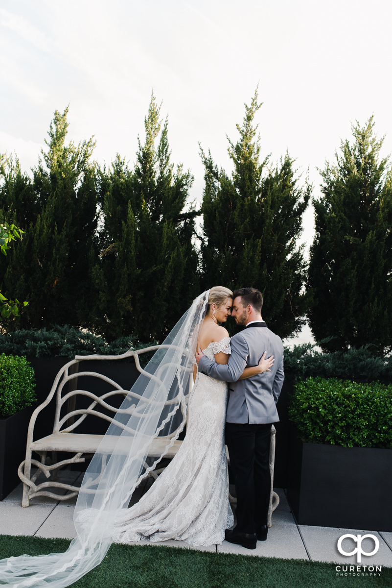 Bride and groom hugging as her long veil blows into the wind after their downtown Greenville,SC rooftop wedding at Avenue.