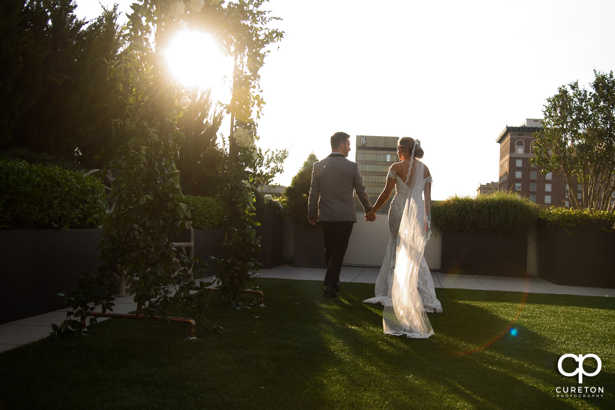Bride and groom walking into the sunset after their downtown Greenville,SC rooftop wedding at Avenue.