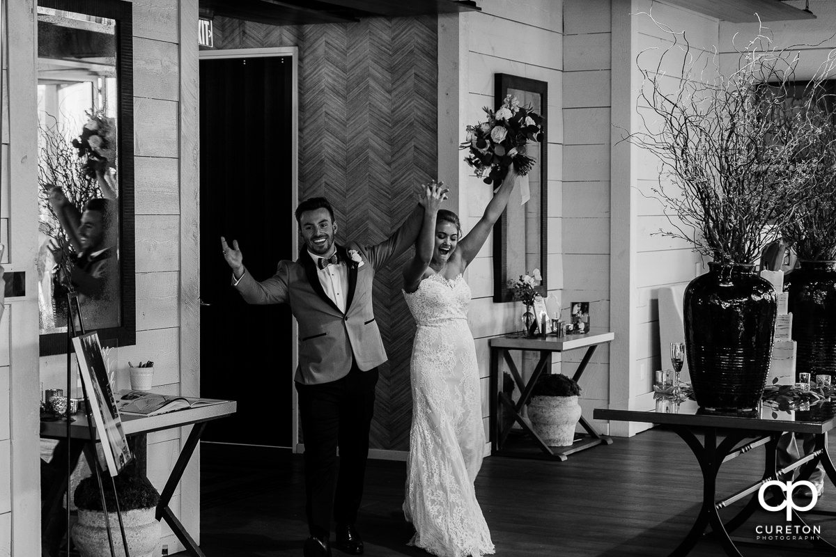 Bride and groom cheering as they are announced into their reception.