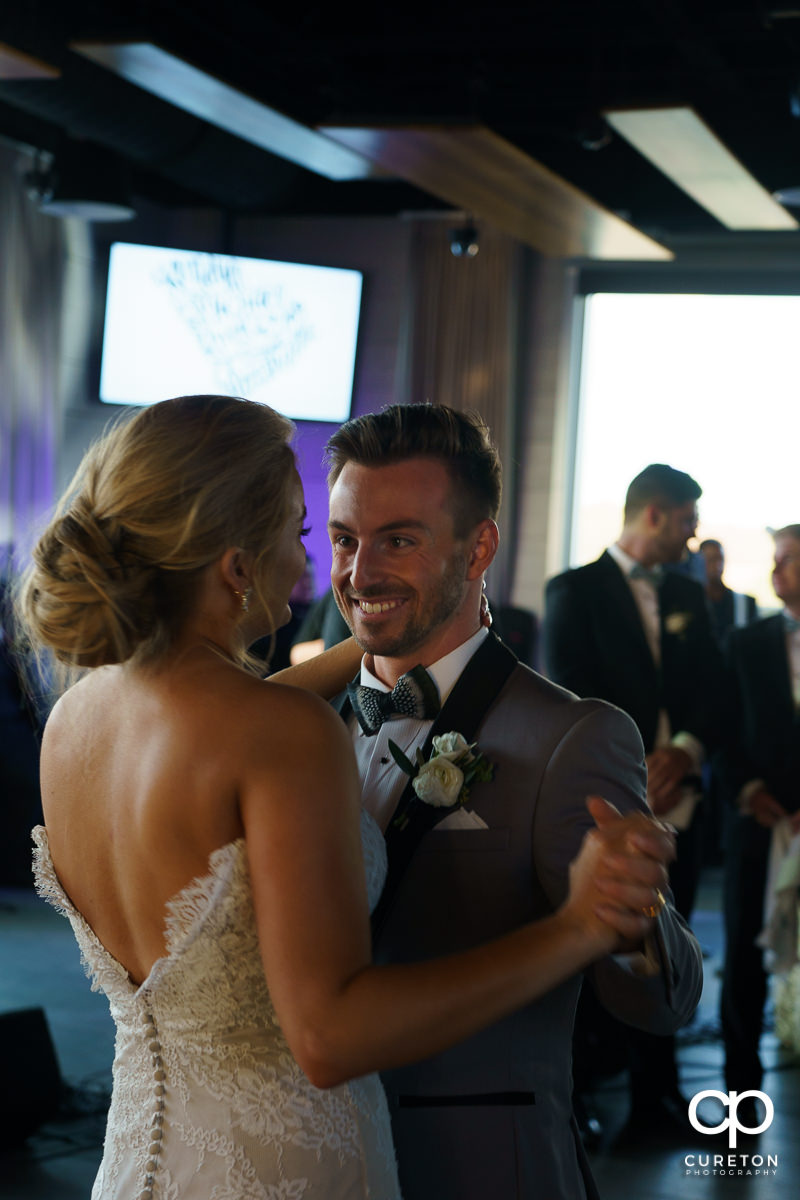 Groom smiling at his bride during their first dance at the wedding reception.
