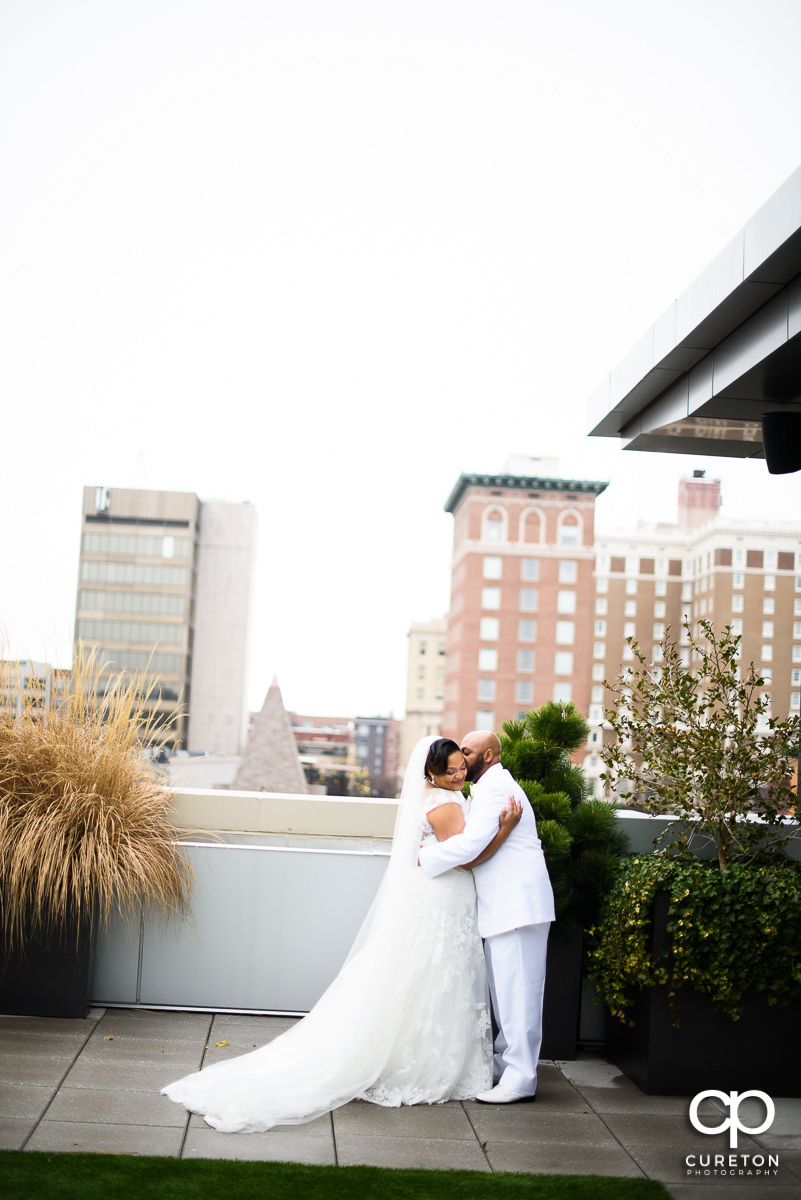 Groom kissing his bride while viewing the downtown Greenville SC skyline during their wedding at Avenue .