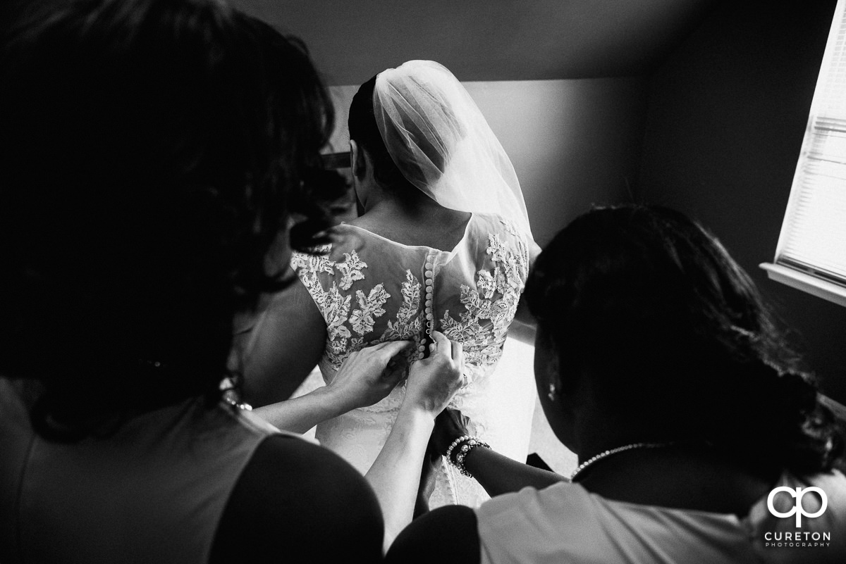 Bride getting into her dress with the help of her bridesmaids.