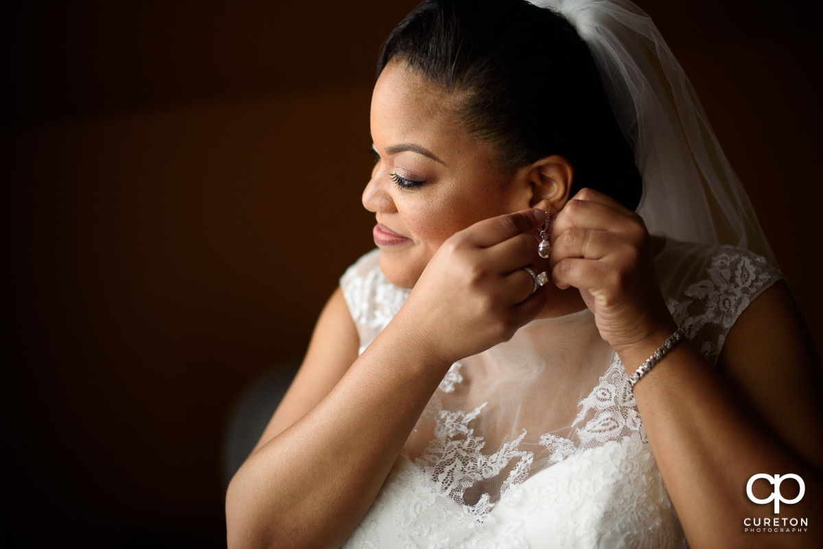 Bride putting her earrings in.
