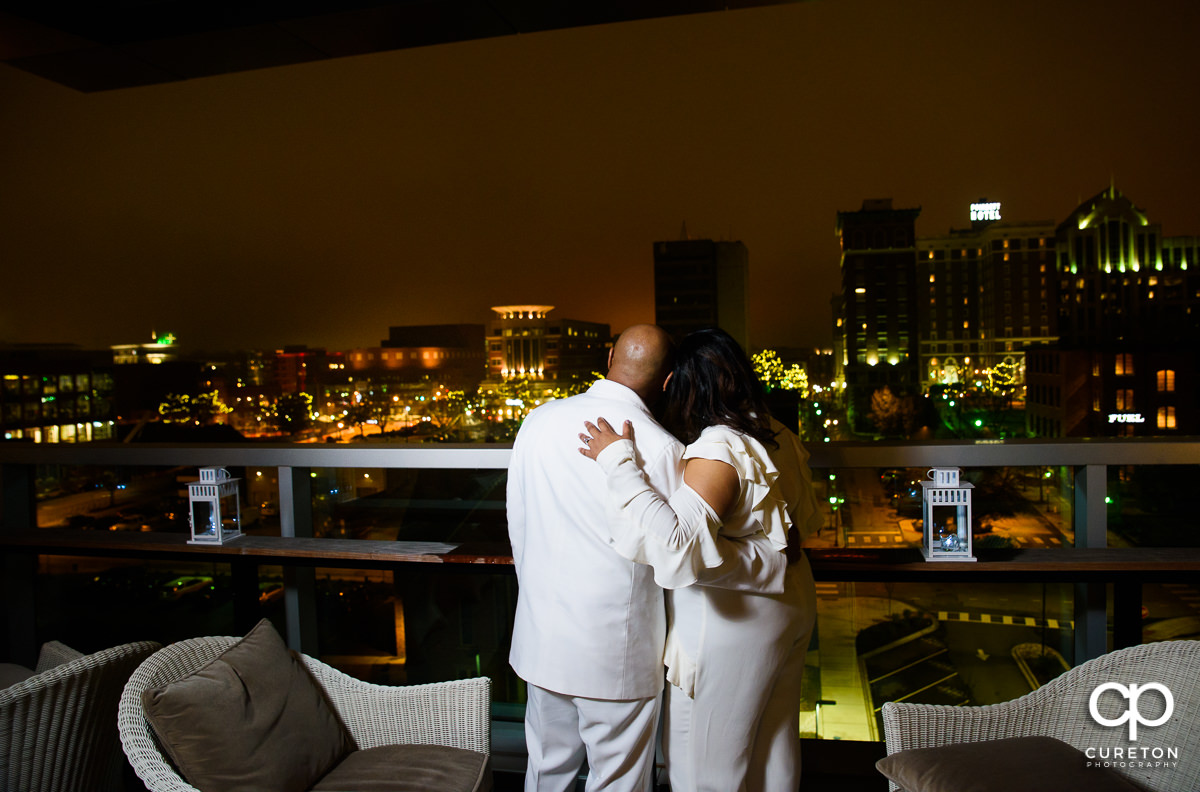Bride and groom looking into the night on the roof.